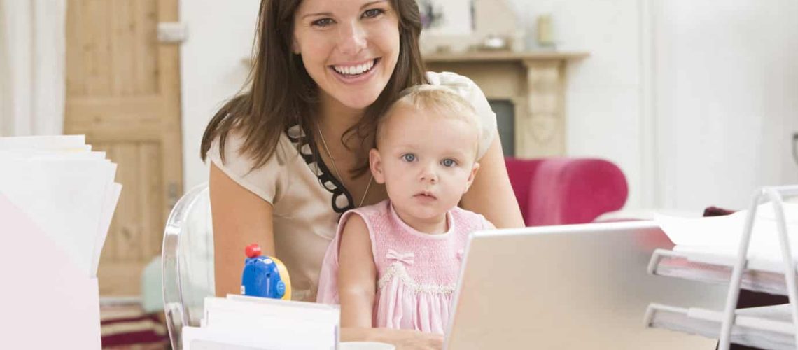 Mother and baby in home office with laptop